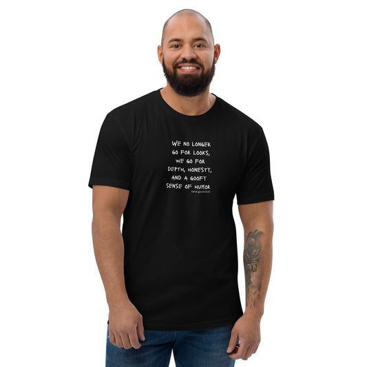 Black t-shirt worn by a gay man, emblazoned with the empowering mantra 'We No Longer Go For Looks' in bold white letters