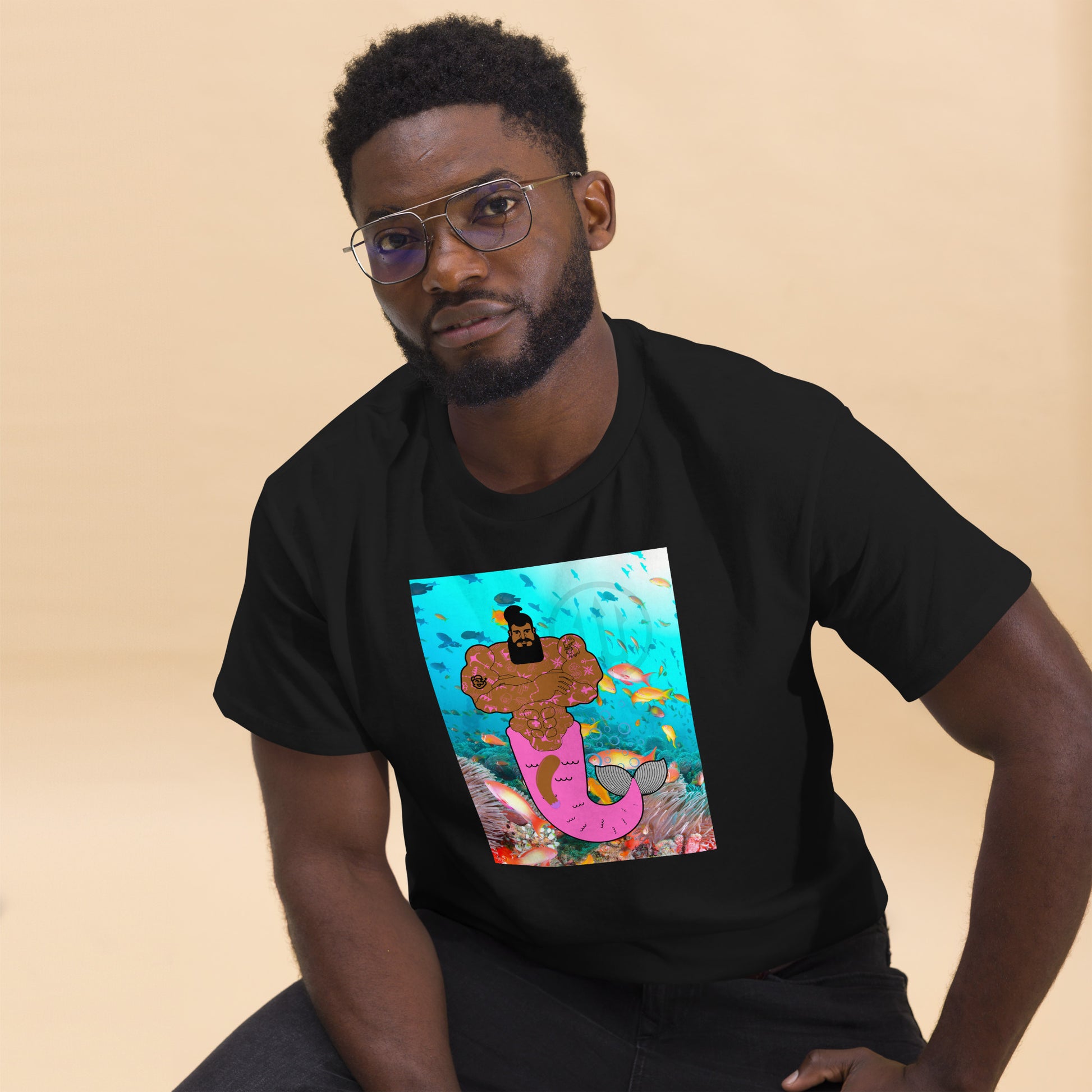 Black t-shirt with a vibrant graphic of a muscular merman covered in tattoos, swimming in a deep blue ocean.